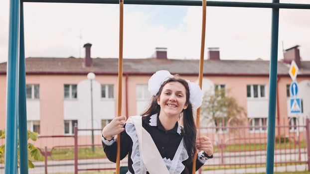 Happy female graduate goes for a swing on the last day of school