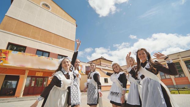 Happy Russian school graduates are stretching their hands on their last school day