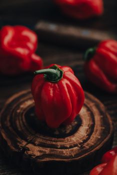 Close Up of Red Habanero Chili Pepper on a Wooden Coaster on a Dark Background