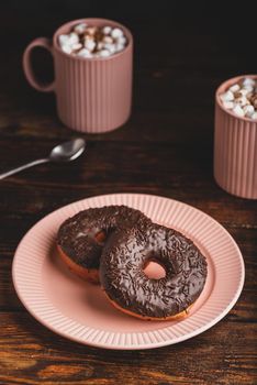 Chocolate Donuts and Mugs of Hot Chocolate with Marshmallow on Rustic Wooden Table