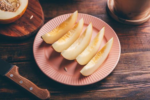 Plate of Sliced Ripe Yellow Melon on Rustic Wooden Table