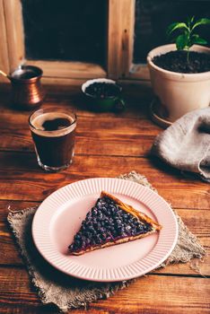 Slice of Fresh Baked Serviceberry Open Pie on Plate and Glass of Turkish Coffee on Wooden Table