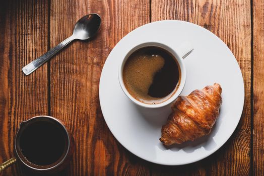 Fresh Croissant and Cup of Coffee on Wooden Surface. View from Above