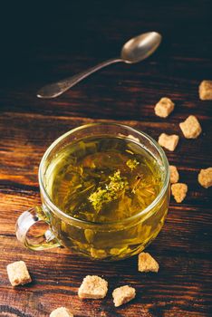 Cup of herbal tea with refined sugar on a wooden background