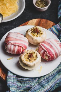 Preparing of bacon-wrapped button mushrooms stuffed with grated cheddar cheese and spices