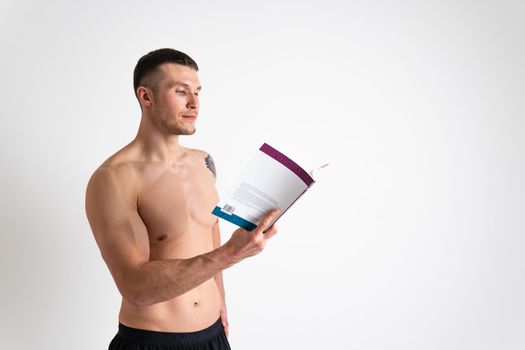 Bodybuilder reads the book on a white background isolated at the bottom of his head on his hands male muscular, athlete glasses chest happy Health manager gym, vision tan