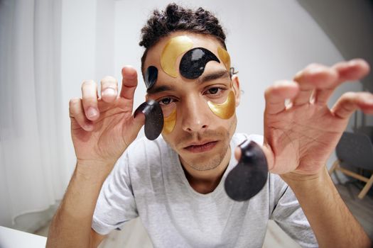 A young man in a white T-shirt with patches on the face rejuvenation skin care. High quality photo