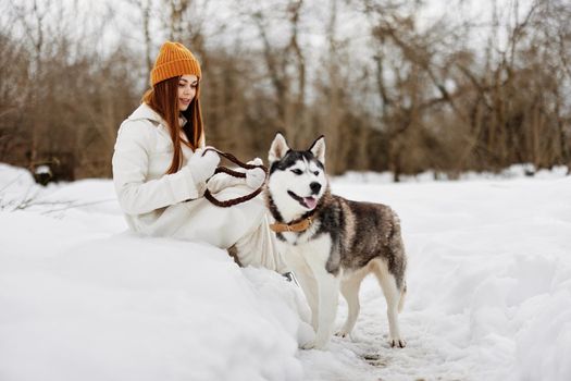 cheerful woman in the snow playing with a dog fun friendship winter holidays. High quality photo