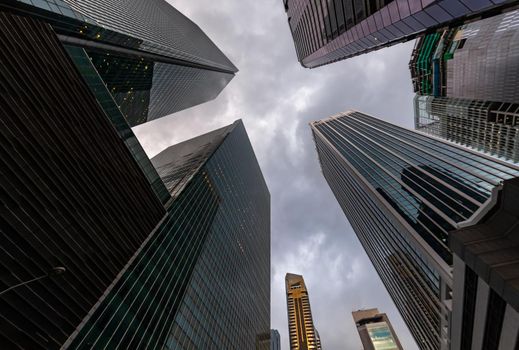 Glass Facades of skyscrapers of the financial district of Singapore on a cloudy evening, bottom view, wide lens, city center, building of large companies without logos. High quality photo