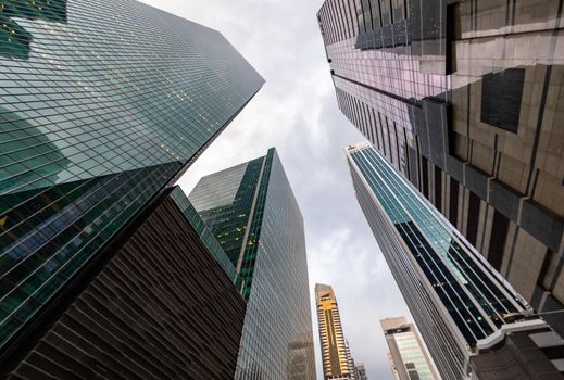 Glass Facades of skyscrapers of the financial district of Singapore on a cloudy evening, bottom view, wide lens, city center, building of large companies without logos. High quality photo