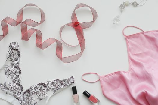 Female underwear with a red ribbon and cosmetics on white background top view