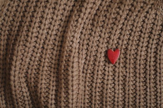 Decorative red heart on beige knitted sweater. Valentines day or love concept