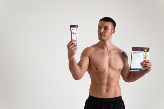 Bodybuilder reads the book on a white background isolated at the bottom of his head on his hands male young reading, muscle fitness torso body intellectual ABS gym, beach tan