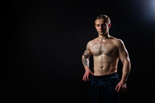 Man on black background keeps dumbbells pumped up in fitness muscle black, athlete strong lifting heavy, shirtless pectoral. Young adult, human fit Look at the press and measures the size of pants for weight loss