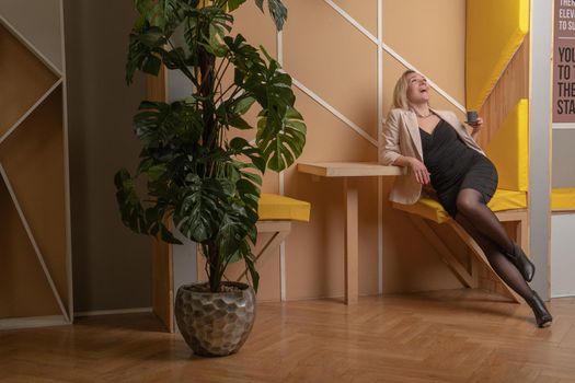 Woman sits on a chair clouded on a yellow background girl office, young people model happy, relaxation. Posing feminine peace joyful