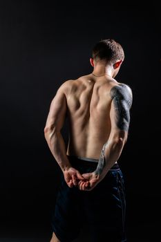 Man on black background keeps dumbbells pumped up in fitness muscle chest body training exercise hold weightlifting. Young sportive power, gym fit back of the arm muscles