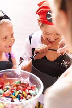 A brother and sister receive sweets from a neighbor on halloween.