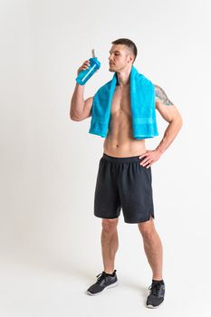 Male drink-water fitness is pumped with a towel on a white background isolated fitness lifestyle, water healthy male bottle holding, muscles cardio. Strength copy tired one muscle