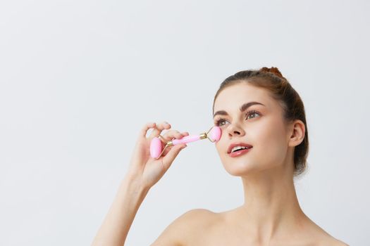 woman pink quartz roller scraper skin care massage bare shoulders close-up Lifestyle. High quality photo