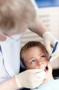 High angle view of doctor checking boys teeth in clinic.