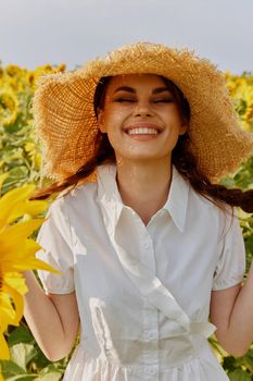 woman portrait in a straw hat in a white dress a field of sunflowers agriculture unaltered. High quality photo