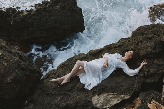 beautiful woman in a secluded spot on a wild rocky coast in a white dress unaltered. High quality photo