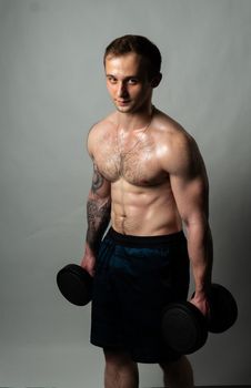 Man on black background keeps dumbbells pumped up in fitness muscle black, body fitness athletic shirtless Attractive handsome adult, one fit dumbbells and body press beautiful on a white background