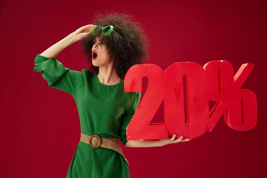 Positive young woman holding red twenty percent discount advertising color background unaltered. High quality photo