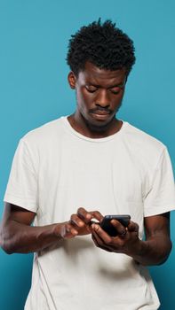 Confused man using smartphone for text messages and browsing internet. Portrait of modern person looking at mobile phone with touch screen for online communication feeling disoriented.