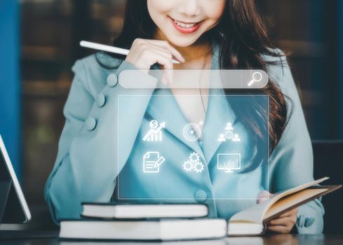 Finance and investment concept, business woman smiling happily as she reads a book to research investment information and analyze stock market direction to manage investment risks