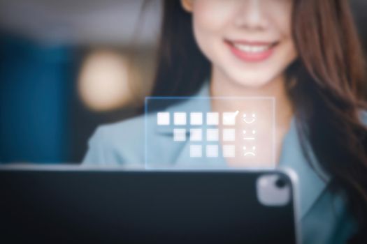 A female entrepreneur or businesswoman showing a smiling face while operating a computer tablet working on a wooden table