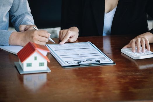 Loan signing concept, refinancing, home and land purchase, rental accommodation, female real estate agent or bank employee pointing to a contract or agreement with a male client to to Buy a dwelling