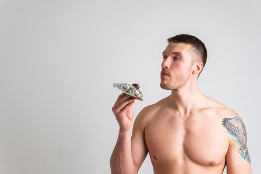 Man eats protein bar on white background isolated healthy, man health person, delicious workout. ABS, cereal female