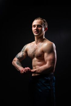 Man on black background keeps dumbbells pumped up in fitness biceps black, body muscular man lifting dumbbell, shirtless Attractive handsome guy fit View from the bottom up good press beautiful muscles hairy chest charisma