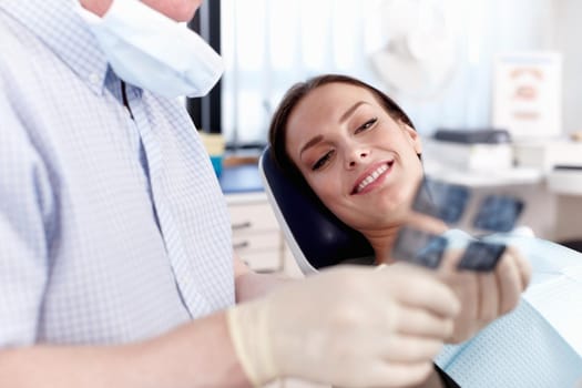 Portrait of dentist showing x-ray to female patient in clinic.