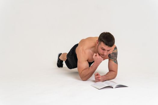 Bodybuilder reads the book on a white background isolated at the bottom of his head on his hands man young glasses background adult, sport. Smile manager biceps, beach tan