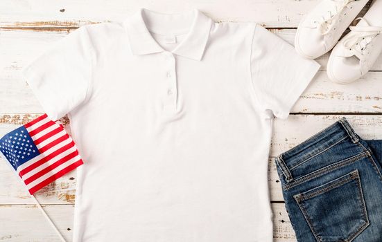 USA Memorial day, Presidents day, Veterans day, Labor day, or 4th of July celebration. Mockup design white polo t shirt for logo, top view on white wooden background with US flag, shoes and jeans