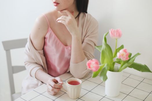 romantic spring portrait of a young woman with tulips at home.