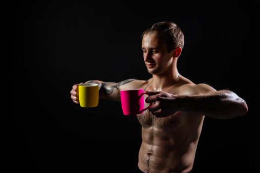 Man on black background keeps dumbbells pumped up in fitness muscle chest arm weight strong bodybuilder powerful, person weightlifting. Lift sportive people fit holds a yellow and pink cup