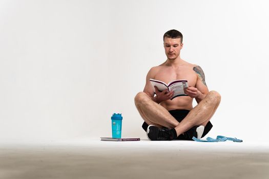 Bodybuilder reads the book on a white background isolated at the bottom of his head on his hands male young macho, bodybuilding chest adult, Health winner biceps, beach tan