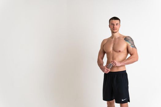 Male drink-water fitness is pumped with a towel on a white background isolated fit body, water gym man person, muscles cardio. Strength pace, tired one muscle