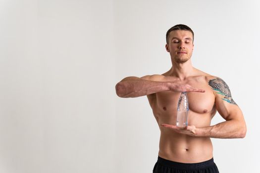 Male drink-water fitness is pumped with a towel on a white background isolated fitness athlete water sport energy guy, cardio. Towel active, tired one muscle