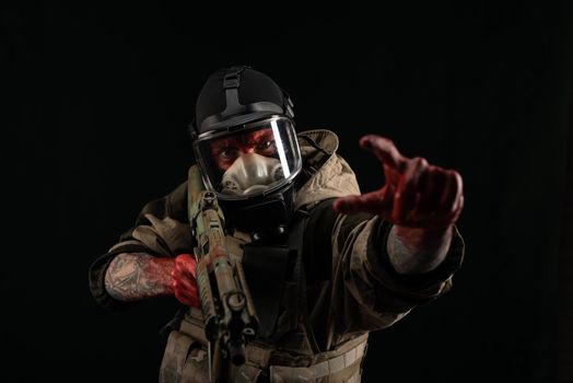 man in a military uniform and a gas mask holds a weapon with bloody hands with an angry expression of emotions