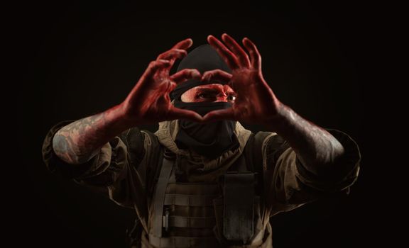 the photo of a man in a military uniform and balaclava with a bloody face and hands up to the elbow in blood on a black background