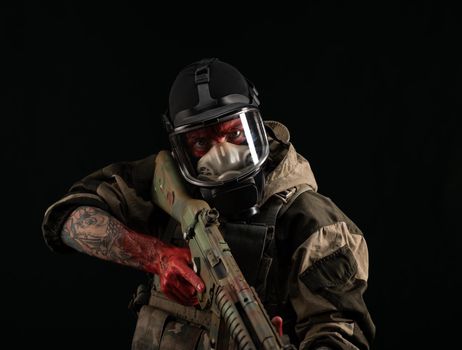 man in a military uniform and a gas mask holds a weapon with bloody hands with an angry expression of emotions