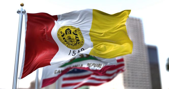 San Diego city flag waving in the wind with California state and United States national flags blurred in background. San Diego municipal flag