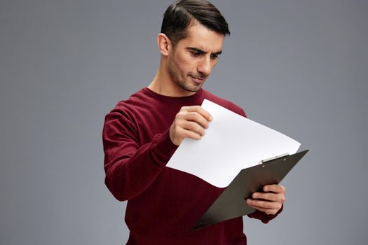 handsome man in a red sweater folder for papers posing business and office concept. High quality photo