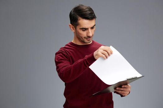 manager looks at the tablet with papers in a red sweater posing Gray background. High quality photo