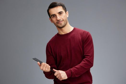 handsome man with a tablet for papers looking at the camera in a red sweater with glasses posing self confidence. High quality photo