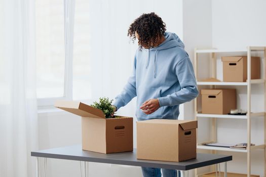 guy with curly hair unpacking things from boxes in the room sorting things out. High quality photo